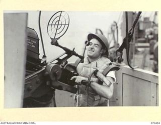 AT SEA, 1944-05-12. MR S. CUE (1), A STEWARD ABOARD THE TROOPSHIP ORMISTON, MANNING AN OERLIKON GUN DURING ANTI-AIRCRAFT PRACTICE ON THE VOYAGE FROM PORT MORESBY TO LAE