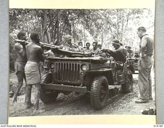 1943-01-22. PAPUA. SANANANDA AREA. A WOUNDED AUSTRALIAN IS PLACED ON A JEEP BY NATIVE BEARERS