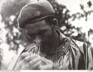 ORODUBI, NEW GUINEA. 1943-07-30. NX114931 LIEUTENANT S. READ, 2/3RD AUSTRALIAN INDEPENDENT COMPANY LIGHTS HIS PIPE AFTER THE SUCCESSFUL ATTACK ON "TIMBERED KNOLL". (FILM STILL)