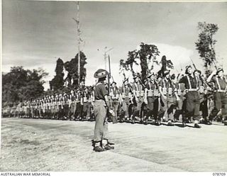 BOUGAINVILLE ISLAND. 1945-01-26. TROOPS OF "A" COMPANY, 24TH INFANTRY BATTALION GIVE "EYES RIGHT" AS THEY MARCH PAST THE SALUTING BASE AT THE CONCLUSION OF THE INSPECTION OF THE UNIT BY THE GENERAL ..