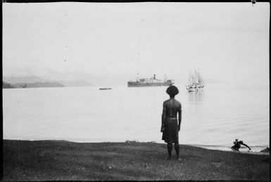 Malaua on a beach with the Burns Philp ship M.V. Montoro and a ketch in the harbour beyond, Salamaua, New Guinea, 1933, 2 / Sarah Chinnery