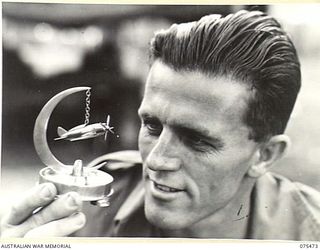 MILILAT, NEW GUINEA. 1944-08-23. QX54142 SIGNALLER E.J. MILLS, 5TH DIVISION SIGNALS SHOWING AN ASH TRAY FITTED WITH A MODEL OF AN AMERICAN "THUNDERBOLT" AIRCRAFT MADE IN HIS SPARETIME