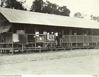 LAE BASE AREA, NEW GUINEA. 1944-12-27. THE ORDERLY ROOM AND ADMINISTRATION BUILDINGS OF THE 13TH WORKSHOPS AND PARK COMPANY. IDENTIFIED PERSONNEL ARE:- NX143062 SERGEANT E. WALTON, ORDERLY ROOM ..