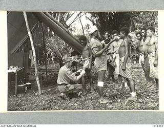 1943-08-04. NEW GUINEA. MUBO CAMPAIGN. FIRST AID AND MEDICINE BEING ADMINISTERED TO NATIVE CARRIERS WITH ALLIED TROOPS IN THE MUBO AREA. THIS NATIVE HOSPITAL IS IN CHARGE OF WARRANT OFFICER W. ..