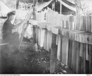 SOPUTA, NEW GUINEA. 1944-06-14/02. CORPORAL T.L. WHITE OF THE 7TH GRAVES REGISTRATION UNIT WRITING THE NAMES OF DECEASED PERSONNEL ON CROSSES AT THE WAR CEMETERY