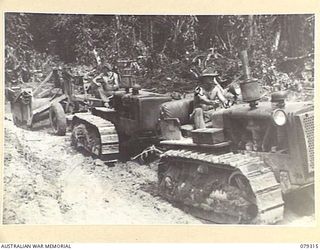 BOUGAINVILLE ISLAND. 1945-03-01. NX157198 SAPPER W. NIXON (1) AND VX118317 SAPPERF. BOURKE (2) OF THE 5TH FIELD COMPANY, USING TWO TRACTORS TO HAUL A CARRY- ALL LOADED WITH SOIL DURING THE ..