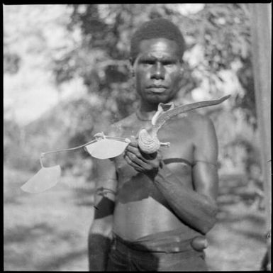 Man holding a pitcher plant flower, Rabaul, New Guinea, ca. 1936 / Sarah Chinnery