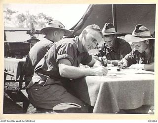 CAPE WOM, WEWAK AREA, NEW GUINEA, 1945-07-11. TROOPS OF HEADQUARTERS 6 DIVISION FILLING IN QUESTIONS ON THE AUSTRALIAN MILITARY FORCES CENSUS FORM. THE CENSUS WILL MAKE AVAILABLE VALUABLE ..