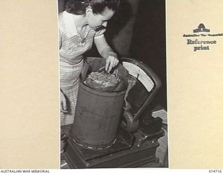 1943-04-28. AUSTRALIA AT WAR. THIS PICTURE SHOWS MRS REVA SCOTT, WHOSE HUSBAND IS AN A.I.F. SOLDIER NOW IN NEW GUINEA, CHECKING THE WEIGHT OF A 15 LB. DRUM OF CARROTS BEFORE IT IS SEALED. (NEGATIVE ..