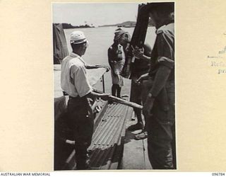 BUKA ISLAND, BOUGAINVILLE AREA, 1945-09-19. JAPANESE NAVAL TROOPS LOADING SWORDS OF JAPANESE OFFICERS, TIED IN BUNDLES OF TEN, ONTO AN AUSTRALIAN MOTOR LAUNCH AT BUKA JETTY, FOR TRANSPORTATION TO ..