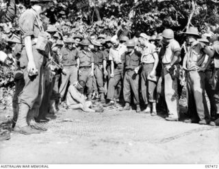 FINSCHHAFEN, NEW GUINEA. 1943-09-22. TROOPS OF THE UNITED STATES ARMY AND THE FINSCHHAFEN FORCE INSPECTING THE FIRST JAPANESE PRISONER TAKEN IN THE BEACHHEAD LANDING