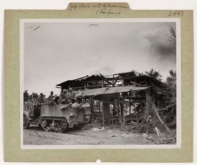 Photograph of a Marine Half-track As It Pauses in Front of a Burned-Out Store on Saipan