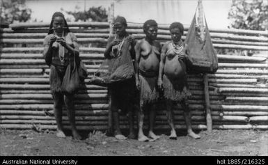 Four women in grass skirts carrying bags