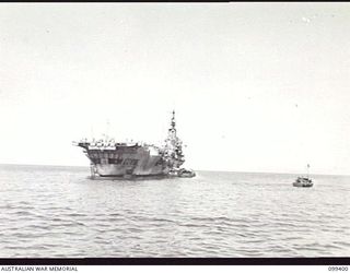 WEWAK HARBOUR, NEW GUINEA, 1945-12-13. THE AIRCRAFT CARRIER HMS IMPLACABLE ANCHORED IN WEWAK HARBOUR. APPROXIMATELY 2,200 MEMBERS OF 6 DIVISION EMBARKED ON THE CARRIER FOR RETURN TO AUSTRALIA