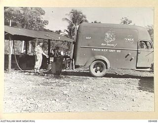 LAE AREA, NEW GUINEA. 1944-12-20. SENIOR REPRESENTATIVE GREEN, YMCA, SUPERVISING THE LOADING OF TEA URNS TO A TRUCK FOR TRANSPORT TO OUTLYING WORKS COYS. THIS SERVICE IS CARRIED OUT TWICE DAILY