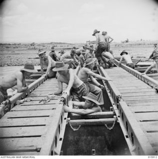 1943-10-02. NEW GUINEA. MARKHAM VALLEY. AUSTRALIAN ENGINEERS BRIDGE A TRIBUTARY OF THE MARKHAM RIVER WHICH FLOWS AT SIX KNOTS AN HOUR. (NEGATIVE BY MILITARY HISTORY NEGATIVES)