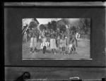 Five men standing with feather head dress.