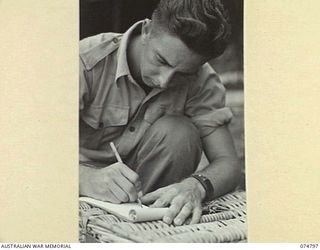 MILILAT, NEW GUINEA. 1944-07-16. A SIGNALLER OF THE 1ST PIGEON SECTION, HEADQUARTERS, 5TH DIVISION, WRITING A MESSAGE FOR DESPATCH BY PIGEON POST TO A UNIT IN THE AREA