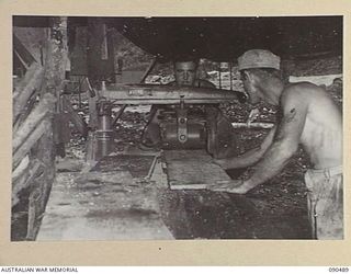 JACQUINOT BAY, NEW BRITAIN. 1945-04-12. PRIVATE J.A. KULIKOWSKI (1), AND SERGEANT R.E. GREENWALD (2), USING AN ELECTRIC SAW IN THE "HALL SHOP". THE MEN ARE MEMBERS OF 3016 ENGINEER BOAT MAINTENANCE ..