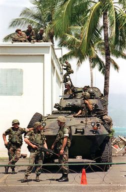 US Marines use the Light Assault Vehicle (LAV-25) and a sniper position on the hoof to guard a building designated as the American Embassy. Marine from the 11th Marine Expeditionary Unit (MEU) Camp Pendleton, Ca trained in simulated Noncombatant Evacuation Operation (NEO) at Kaneohe Bay Marine Corps Station, HI during Operation RIMPAC 96. One Marine is armed with the 5.56mm M16A2 assault rifle with the M203 grenade launcher attached while the LAV-25 is armed with the 25mm M242 "Bushmaster" chain gun and a 7.62mm M240G machine gun atop the turret