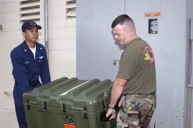 US Navy (USN) Lieutenant (LT) Pete Obenauer and USN Hospital Corpsman Second Class (HM2) Richard Cabatit, Naval Environmental and Preventive Medicine Unit 6 (NEPMU-6) carry an entomology vector surveillance and control kit to an uploading point as they prepare for deployment to Indonesia. The entomology kits are used to trap mosquitoes, ticks and other disease carrying insects for examination and possible extermination if discovered to be carriers of malaria or dengue fever. NEPMU-6 is deploying to Indonesia to provide humanitarian support and conduct water quality testing, insect collection and examination for disease, and medical assistance as part of larger disaster relief efforts...