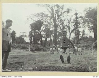 BOUGAINVILLE. 1945-04-25. PRIVATE J.E. FORD, 26 INFANTRY BATTALION, COMPETING IN THE LONG JUMP AT THE 2/3 CONVALESCENT DEPOT TABLOID SPORTS. THIS IS PART OF THE REMEDIAL TREATMENT FOR SOLDIERS ..
