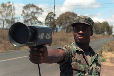 SPECIALIST Fourth Class (SPC) Charles Bivens of the 25th Military Police Company uses a K15 radar gun to monitor traffic along Saddle Road during Exercise OPPORTUNE JOURNEY 4-84 at the Pohakuloa Training Area