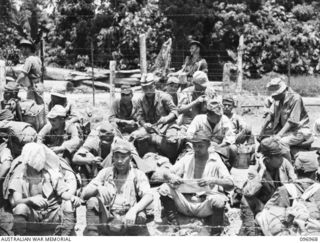 TOROKINA, BOUGAINVILLE. 1945-09-23. JAPANESE NAVAL TROOPS SITTING DOWN ON ARRIVAL AT A COMPOUND SOUTH OF THE TOROKINA RIVER. THEY ARE UNDER THE CONTROL OF OFFICERS OF 9 INFANTRY BATTALION. THE ..