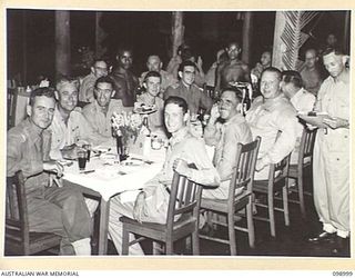 LAE, NEW GUINEA. 1945-11-25. A PARTY OF OFFICERS BEING SERVED THEIR MEAL BY NATIVE WAITERS AT THE AUSTRALIAN ARMY CANTEENS SERVICE OFFICERS' CLUB. THE CLUB IS SITUATED ON THE BANKS OF THE BUSU ..