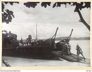 PIEDU ISLAND, BOUGAINVILLE AREA. 1945-09-29. JAPANESE TROOPS FROM THE BUIN AREA UNLOADING GEAR FROM AN AUSTRALIAN LANDING BARGE AT A CONCENTRATION AREA ON PIEDU ISLAND. THE SURRENDER PARTY FROM ..