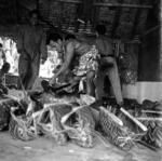 Preparation of feast? Food laid out in palm frond baskets, cutting pig with machete