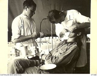 KILIGIA, NEW GUINEA. 1944-03-13. VX81008 CAPTAIN W.A. DOTT (1), OFFICER COMMANDING "E" SECTION, 2/5TH DENTAL UNIT, FILLING A TOOTH FOR VX56169 GUNNER A.S.L. CLARKE (3) OF THE 2/14TH FIELD REGIMENT ..