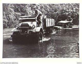 BOUGAINVILLE. 1945-07-21. A 3-TON VEHICLE OF 2/11 FIELD REGIMENT TOWING A JEEP ACROSS THE FLOODED OGORATA RIVER. OWING TO HEAVY RAINFALL THE RIVERS ARE NOW IMPASSABLE TO JEEP TRAFFIC