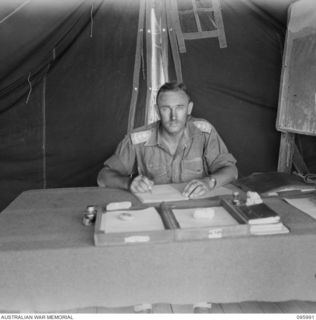 CAPE WOM, WEWAK AREA, NEW GUINEA. 1945-09-01. LIEUTENANT COLONEL J.A. BISHOP, G1, IN HIS OFFICE AT HEADQUARTERS 6 DIVISION