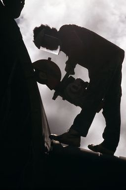 A worker applies a power cutter to the body of a B-52D aircraft, one of three that are being dismantled in accordance with the SALT II treaty between the United States and the Soviet Union