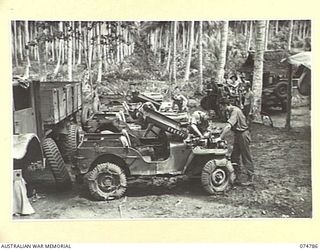 MILILAT, NEW GUINEA. 1944. MECHANICS OF THE 231ST LIGHT AID DETACHMENT, ATTACHED TO HEADQUARTERS, 5TH DIVISION, OVER-HAULING SOME OF THE UNIT MOTOR VEHICLES