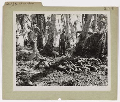 Photograph of Coast Guardsmen Looking at the Bodies of Japanese Killed While Defending Makin Island