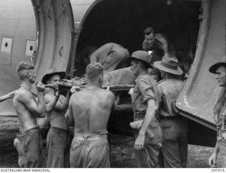 NADZAB AIRSTRIP, NEW GUINEA. 1943-09-18. A WOUNDED AUSTRALIAN SOLDIER BEING LOADED INTO AN AIRCRAFT FOR TRANSPORT BACK TO A BASE HOSPITAL