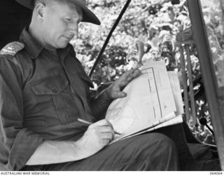 NAMBARIWA, NEW GUINEA. 1944-01-21. NX112720 MAJOR E.W. GREGORY, BRIGADE MAJOR, 8TH INFANTRY BRIGADE STUDYING A MAP OF SIO WHERE MEMBERS OF THE 8TH INFANTRY BRIGADE ARE PATROLLING