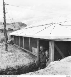 DUMPU, NEW GUINEA. 1944-01-11. VX20488 MAJOR A. WALTERS (1) AND VX15114 SERGEANT W. J. EDWARDS (2) AT THE DOORWAY OF THE 7TH DIVISION SIGNALS WIRELESS TELEPHONE RECEIVING HUT