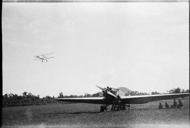 Man servicing a mono plane and a bi-plane in the sky, New Guinea, ca. 1935 / Sarah Chinnery