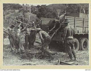 BOIKEN AREA, AITAPE-WEWAK SECTOR. 1945-04-28. MEMBERS OF 2/1 TANK ATTACK REGIMENT DIGGING A PIT FOR THE TRAIL WHILE MOUNTING A 75MM PACK HOWITZER ON THE BACK OF A TRUCK TO ATTAIN A HIGH ELEVATION ..