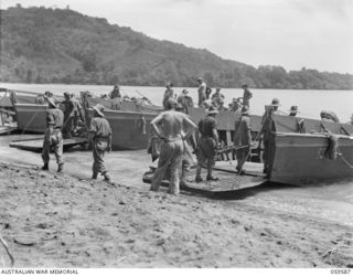 LANGEMAK BAY, NEW GUINEA, 1943-10-28. MEMBERS OF THE 2/24TH AUSTRALIAN INFANTRY BATTALION BOARDING BARGES AT THE BEACHHEAD