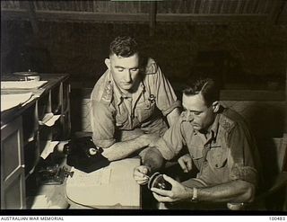 Port Moresby, New Guinea. 1944-05-30. Lieutenant Colonel L. C. Fisher, Chief Electrical and Mechanical Engineer, Moresby Base Sub Area (right), discussing an equipment problem with Colonel H. R. D. ..