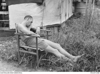 Madang, New Guinea, 1945-08-15. Willie Castles, a RAAF officer serving with Headquarters, RAAF Northern Command (NORCOM), dozes in a chair in the open after celebrating Victory in the Pacific (VP) ..