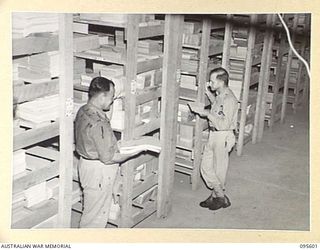 LAE AREA, NEW GUINEA. 1945-08-30. PRIVATE P.R. MCLEOD (1) AND CORPORAL N.T. HANSEN (2) MEMBERS OF 9 LINES OF COMMUNICATION STATIONERY DEPOT, CHECKING STOCKS IN THE BOOKS AND FORM SECTION