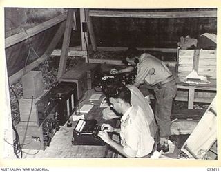 LAE AREA, NEW GUINEA. 1945-08-31. RADIO NEWS COMING IN TO THE ARMY NEWSPAPER, GUINEA GOLD. THE MONITORS ARE ALL FORMER AUSTRALIAN NEWSPAPERMEN AND THE OFFICE OPERATES ROUND THE CLOCK WITH SHORTHAND ..