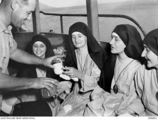 VUNAPOPE, NEW BRITAIN. 1945-09-16. MAJOR L.W. HEINICKE, FIRST ARMY, HANDING COFFEE TO SISTERS ON BOARD THE MOTOR LAUNCH GLORIA. SISTERS AND PRIESTS ARE BEING EVACUATED FROM THE MISSION IN RAMALE ..