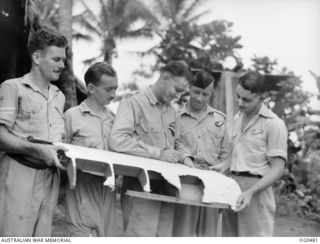 VIVIGANI, GOODENOUGH ISLAND, PAPUA. C. 1944-01-29. WRECKAGE OF BOMB BAY DOOR OF A BEAUFORT BOMBER AIRCRAFT OF NO. 6 SQUADRON RAAF BEING AUTOGRAPHED BY MEMBERS OF THE CREW OF THE AIRCRAFT. LEFT TO ..