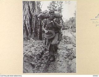 SOUTH BOUGAINVILLE. 1945-07-29. GUNNER W. JONES, 2 FIELD REGIMENT, ROYAL AUSTRALIAN ARMY, FOUND IT HARD GOING THROUGH HEAVY MUD ON THE BUIN ROAD, WEST OF THE OGORATA RIVER, CARRYING HIS GEAR WHILE ..